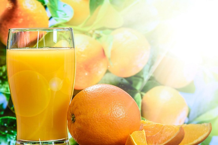 imagem de um copo de laranja com uma laranja ao lado