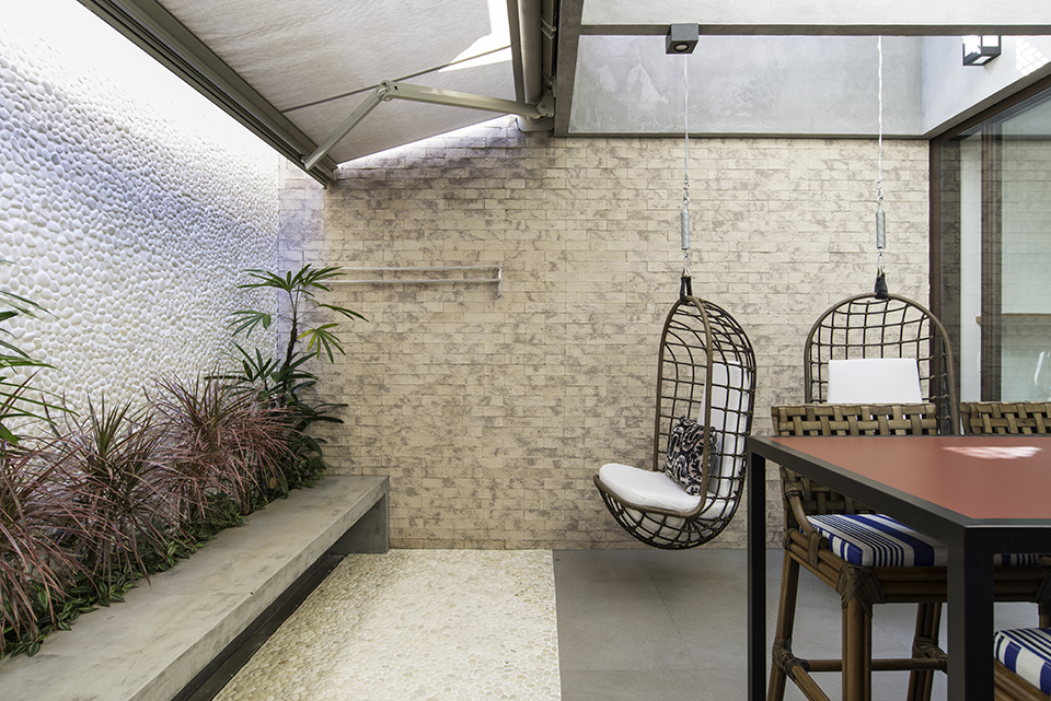 Uma sala de jantar integrado a área gourmet, nesta residência praiana. As poltronas suspensas projetadas pela arquiteta deixou o ambiente com maior amplitude.