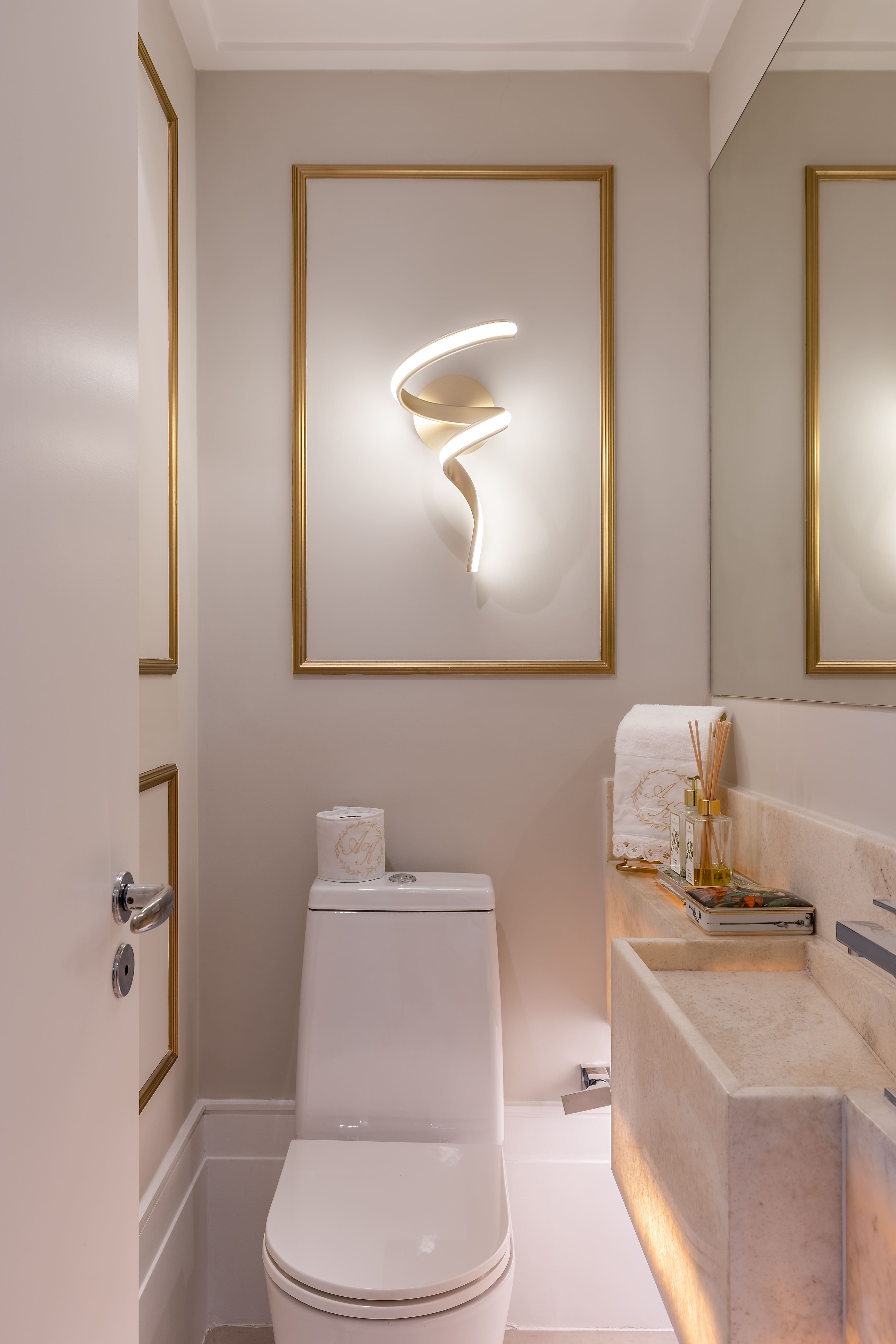 O dourado e a pedra ônix da bancada com cuba esculpida se destacam no lavabo.