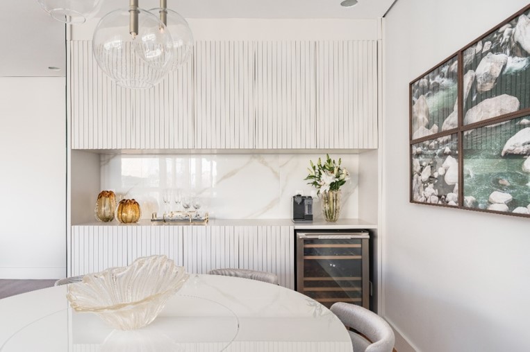 A decoração minimalista e neutra do décor do apartamento é refletida também no cantinho, com apenas um arranjo floral ao lado da máquina.