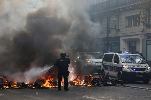 Policial apaga fogo em bicicletas em rua de Paris durante protestos ocorridos no dia 17 de outubro na França